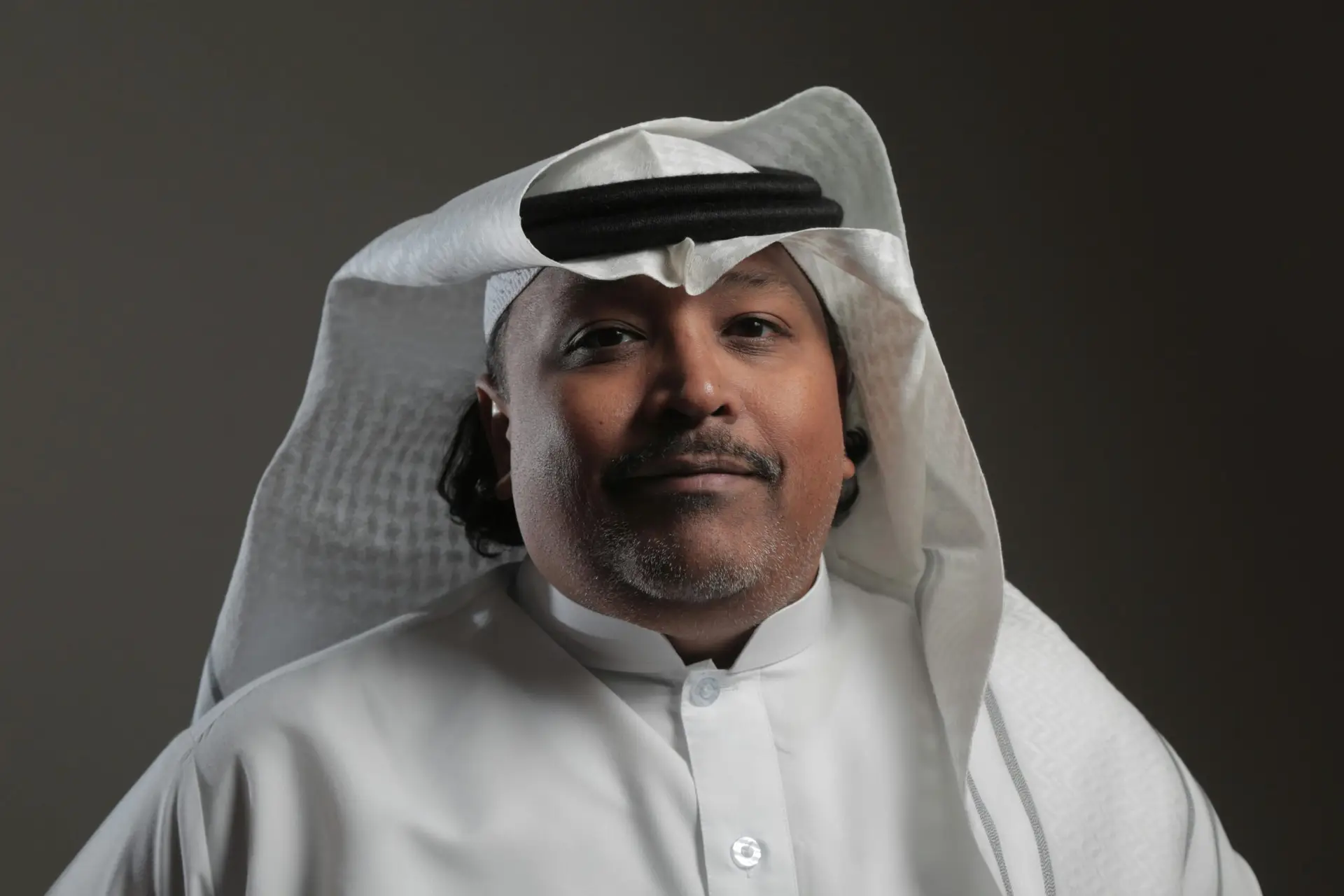 Portrait of a middle-aged Arabic man in traditional attire with a neutral background.