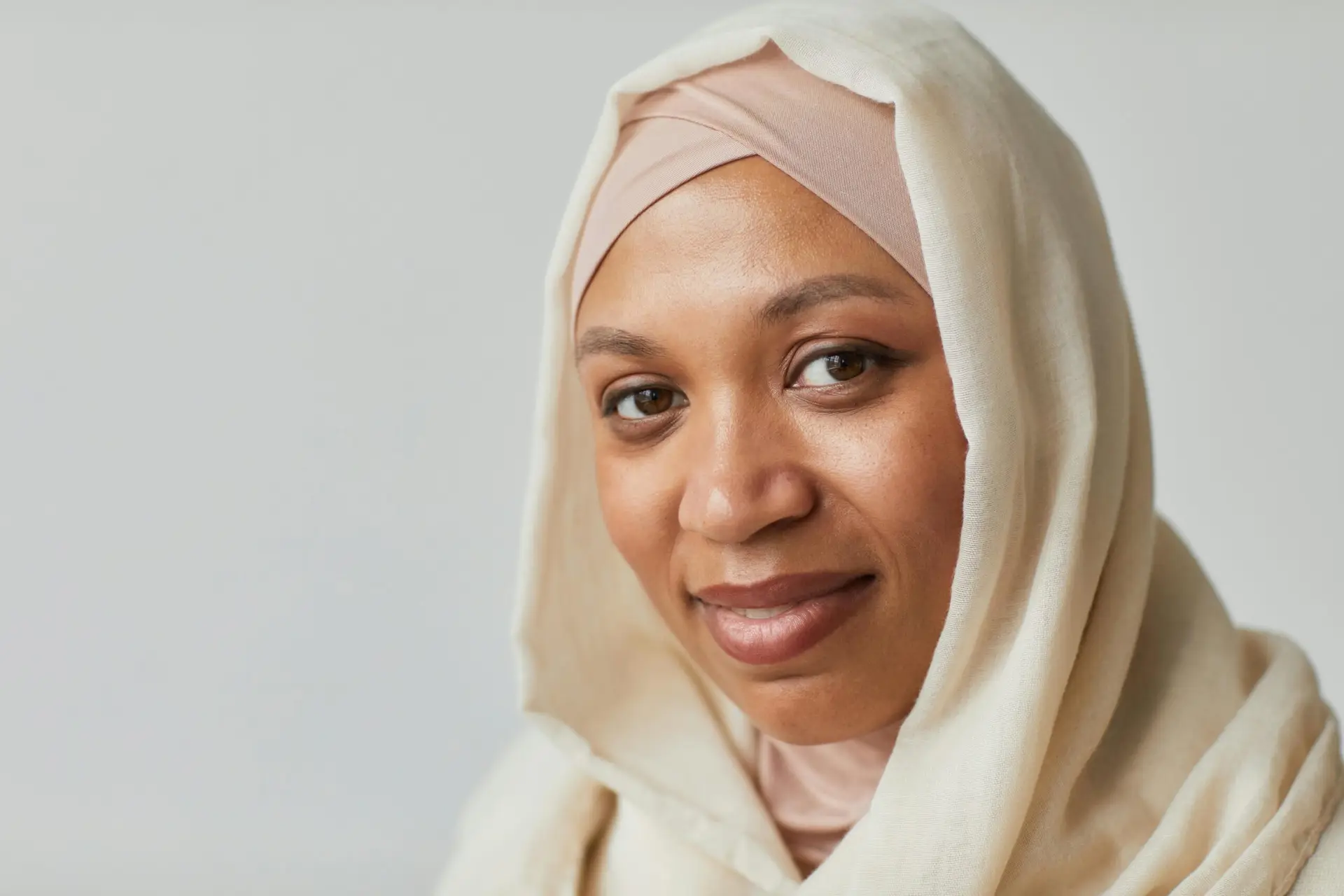 Close-up portrait of a smiling woman wearing a hijab, expressing warmth and confidence.